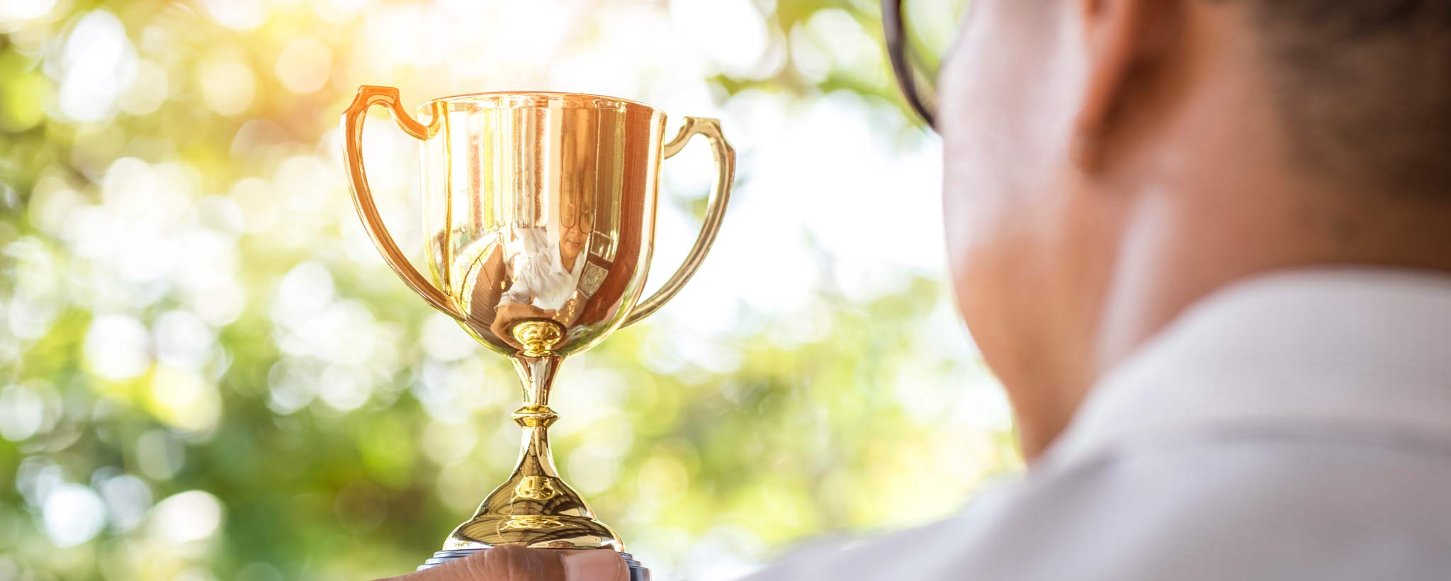 Hand of businessman holding gold trophy