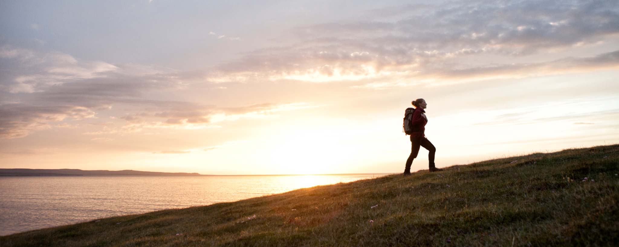 hiker at sunrise by lake hero Hiker by lake at sunrise