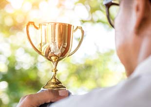 Hand of businessman holding gold trophy