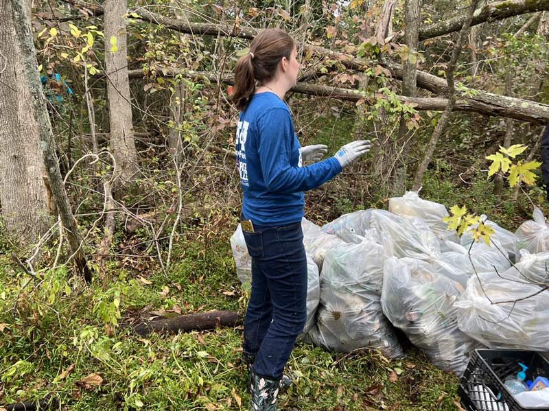 Amanda Seale helps to load a pile of trash bags
    full of litter onto a trash boat. 