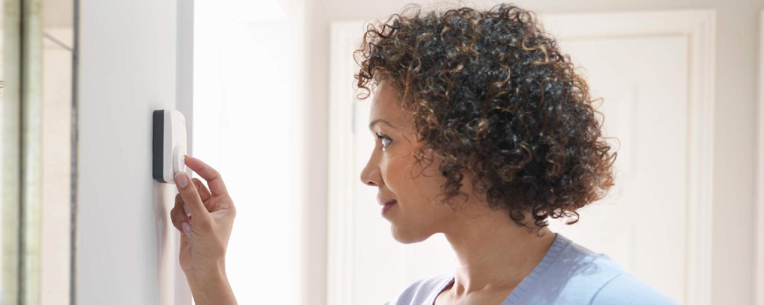 Woman adjusting thermostat in home