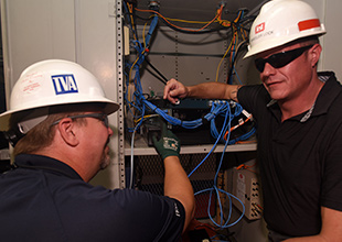 Engineers Rich Ellis and Bradley Gatewood connect fiber optic cables to boost data speed at Joe Wheeler Lock.
