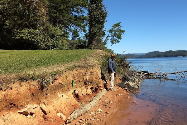 Lakefront property owner standing on the shore looking at the shoreline erosion 